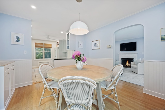 161 Crestwood Rd, Fairfield, CT 06824 - dining area featuring a wainscoted wall, a lit fireplace, light wood finished floors, recessed lighting, and crown molding