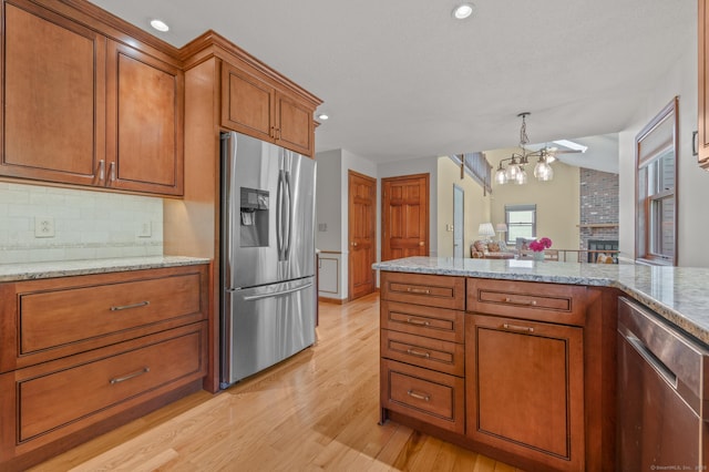 31 S Meadow Ln, Enfield, CT 06082 - kitchen with appliances with stainless steel finishes, brown cabinets, a chandelier, light wood-type flooring, and tasteful backsplash