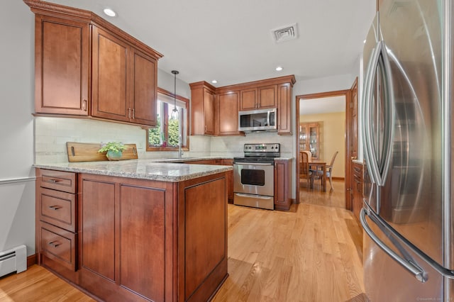 31 S Meadow Ln, Enfield, CT 06082 - kitchen with appliances with stainless steel finishes, brown cabinetry, light wood finished floors, a peninsula, and decorative backsplash