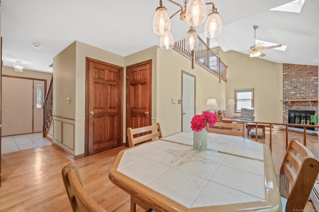 31 S Meadow Ln, Enfield, CT 06082 - dining area featuring light wood-style flooring, a ceiling fan, a brick fireplace, a skylight, and a wainscoted wall