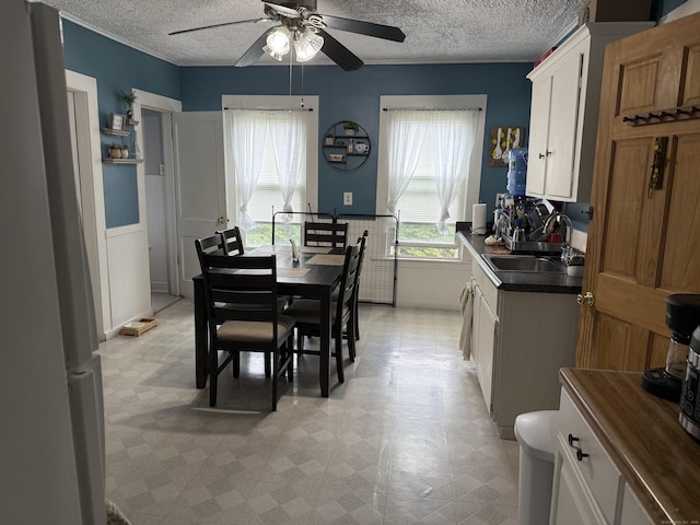 39 Swain Ave, Meriden, CT 06450 - dining space featuring ceiling fan, a textured ceiling, wainscoting, and light flooring