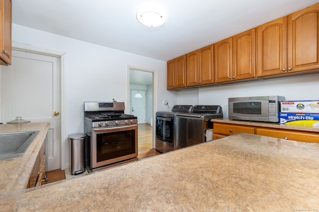 45 Valley Rd, Hamden, CT 06514 - kitchen featuring stainless steel appliances, washer and dryer, light countertops, a sink, and brown cabinetry