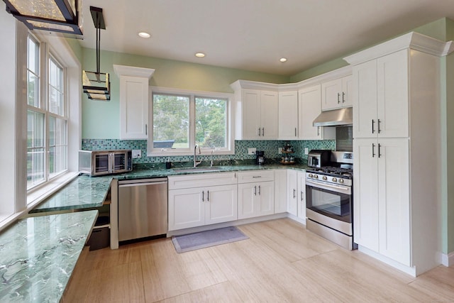 9 Purdum Rd, New Fairfield, CT 06812 - kitchen with stainless steel appliances, under cabinet range hood, a sink, dark stone countertops, and white cabinets