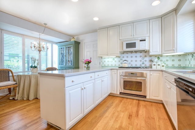 510 W Lyon Farm Dr Unit 510, Greenwich, CT 06831 - kitchen featuring stainless steel oven, dishwashing machine, a chandelier, a peninsula, and light wood-style flooring
