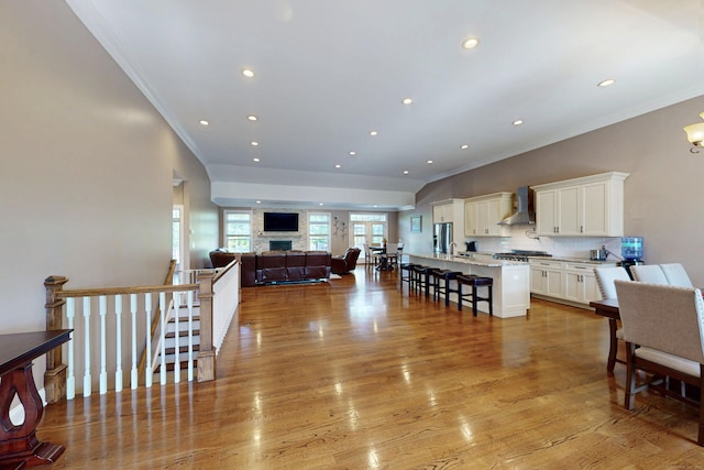 125 Stadley Rough Rd, Danbury, CT 06811 - kitchen with wall chimney exhaust hood, open floor plan, crown molding, a kitchen bar, and white cabinets