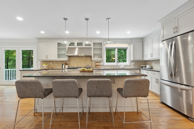 24 Pine Mountain Rd, Redding, CT 06896 - kitchen with stainless steel fridge, under cabinet range hood, a breakfast bar area, a center island with sink, and backsplash
