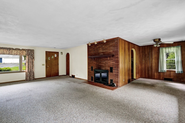 5 Reservoir Rd, Norwich, CT 06360 - unfurnished living room featuring arched walkways, carpet floors, a fireplace, a ceiling fan, and wood walls