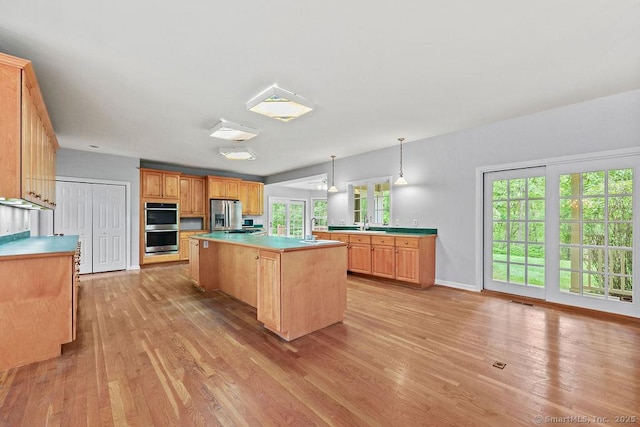 657 Tamarack Rd, Cheshire, CT 06410 - kitchen featuring stainless steel appliances, light wood-style floors, light countertops, a kitchen island, and a sink