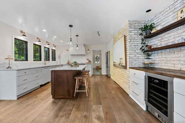 30 Norfield Woods Rd, Weston, CT 06883 - kitchen with beverage cooler, dishwasher, freestanding refrigerator, brick wall, and a kitchen island