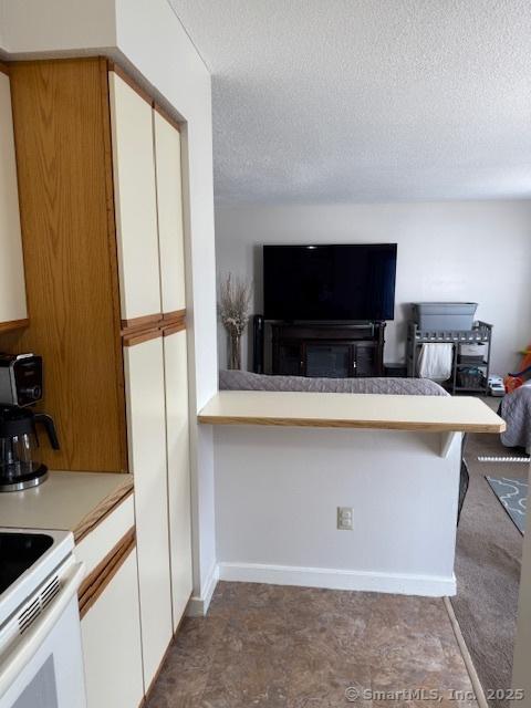 9 Staffordshire Commons Dr Unit 9, Wallingford, CT 06492 - kitchen featuring white cabinets, light countertops, open floor plan, a textured ceiling, and electric stove