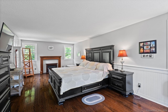 3 Colonial Dr, Clinton, CT 06413 - bedroom with dark wood finished floors, wainscoting, a textured ceiling, a fireplace, and a baseboard heating unit