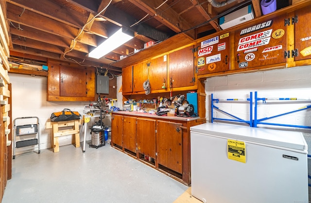 1 Trumbull St, Vernon, CT 06066 - unfinished below grade area featuring refrigerator, electric panel, and a workshop area