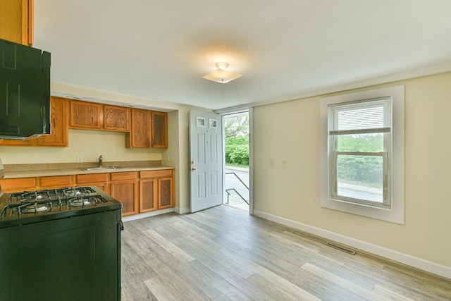 96 Water St, Killingly, CT 06239 - kitchen featuring black gas range, a sink, baseboards, light wood-style floors, and light countertops