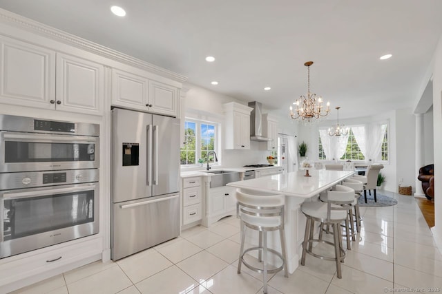 197 Shadow Pond Ln, Suffield, CT 06078 - kitchen featuring appliances with stainless steel finishes, wall chimney range hood, a sink, a chandelier, and a breakfast bar area