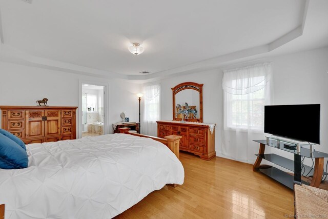 197 Shadow Pond Ln, Suffield, CT 06078 - bedroom featuring a raised ceiling, multiple windows, light wood-style flooring, and ensuite bathroom