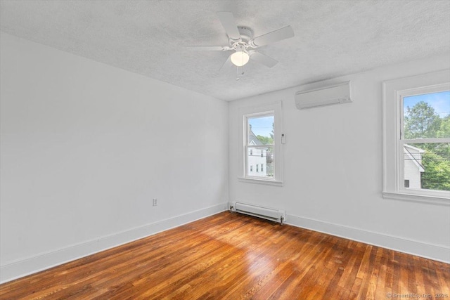 37 Park Ave, Hamden, CT 06517 - spare room with a baseboard radiator, a wall unit AC, a textured ceiling, plenty of natural light, and hardwood / wood-style flooring