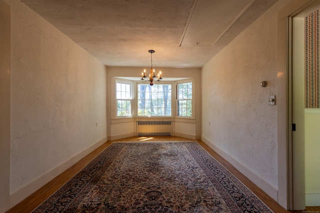 121 Warren Ave, Groton, CT 06355 - unfurnished dining area with radiator, wood finished floors, attic access, a textured wall, and a chandelier