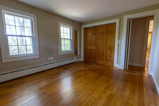 121 Warren Ave, Groton, CT 06355 - unfurnished bedroom featuring baseboard heating, hardwood / wood-style flooring, wallpapered walls, and a closet
