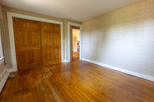 121 Warren Ave, Groton, CT 06355 - unfurnished bedroom with hardwood / wood-style flooring, a baseboard heating unit, a closet, wallpapered walls, and baseboards