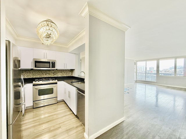 25 Forest St Unit 11A, Stamford, CT 06901 - kitchen featuring stainless steel appliances, dark countertops, a sink, crown molding, and a chandelier