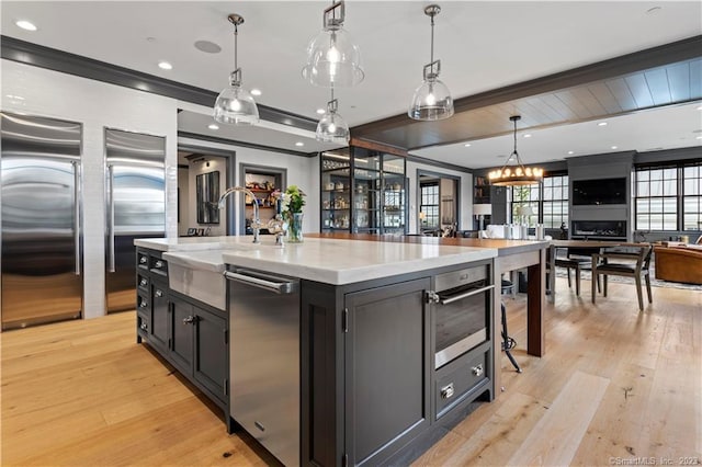 66 High St Unit 17, Guilford, CT 06437 - kitchen featuring open floor plan, appliances with stainless steel finishes, hanging light fixtures, light wood-type flooring, and dark cabinetry