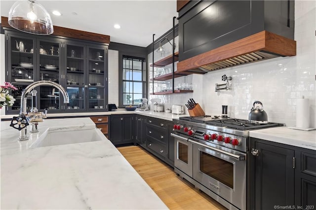 66 High St Unit 17, Guilford, CT 06437 - kitchen featuring range with two ovens, a sink, dark cabinets, light stone countertops, and light wood-style flooring
