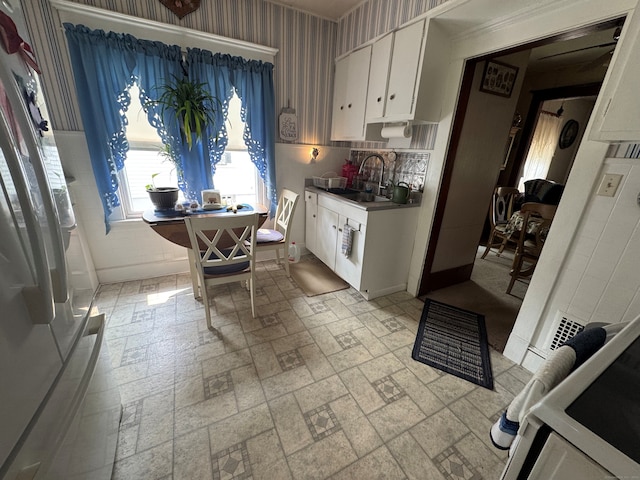 165 Dodge Ave, East Haven, CT 06512 - kitchen featuring freestanding refrigerator, a sink, white cabinets, brick patterned flooring, and wallpapered walls