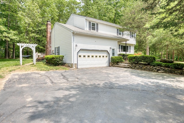 24 Marbella Ln, Tolland, CT 06084 - view of front facade featuring asphalt driveway, a chimney, and a garage