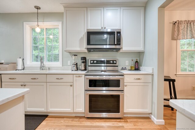 24 Marbella Ln, Tolland, CT 06084 - kitchen featuring stainless steel appliances, light countertops, a sink, light wood-style floors, and pendant lighting