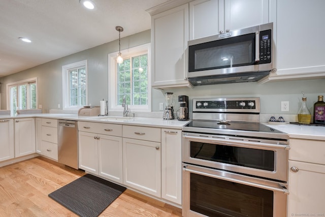 24 Marbella Ln, Tolland, CT 06084 - kitchen featuring stainless steel appliances, a sink, light wood finished floors, light countertops, and plenty of natural light