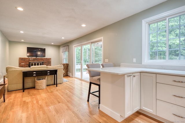 24 Marbella Ln, Tolland, CT 06084 - kitchen featuring white cabinetry, light wood-style floors, recessed lighting, open floor plan, and a kitchen bar