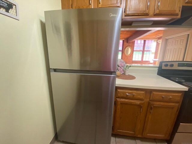 839 Main St Apt 35, Torrington, CT 06790 - kitchen featuring freestanding refrigerator, range with electric cooktop, light countertops, light tile patterned floors, and brown cabinets