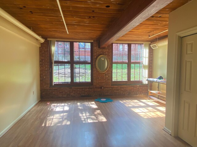 839 Main St Apt 35, Torrington, CT 06790 - empty room with wooden ceiling with exposed beams, brick wall, wood finished floors, and baseboards