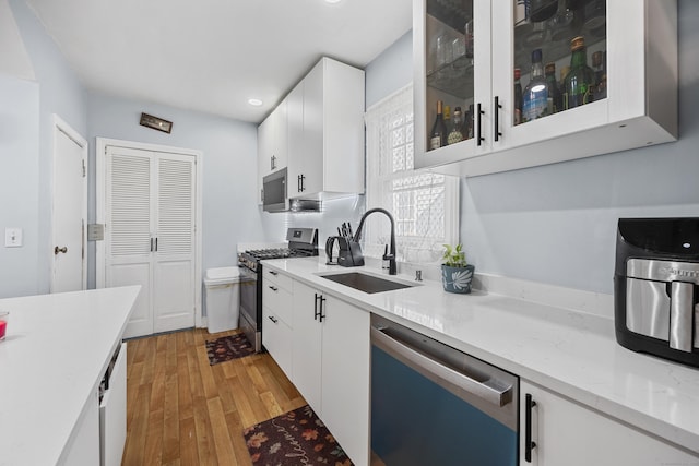 26 Herkimer St, Waterbury, CT 06710 - kitchen with stainless steel appliances, a sink, white cabinets, light wood finished floors, and glass insert cabinets