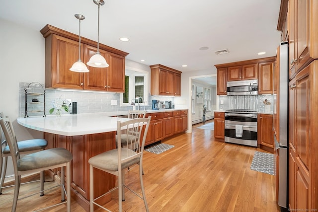 67 Great Hill Rd, Ridgefield, CT 06877 - kitchen featuring stainless steel appliances, a peninsula, brown cabinets, a kitchen breakfast bar, and recessed lighting