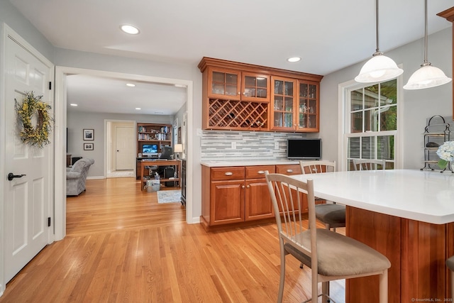 67 Great Hill Rd, Ridgefield, CT 06877 - kitchen with brown cabinetry, a breakfast bar, light wood-style floors, light countertops, and decorative backsplash