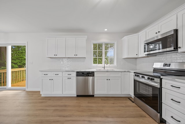 23 Shadybrook Ln, Waterbury, CT 06706 - kitchen featuring stainless steel appliances, decorative backsplash, white cabinetry, light wood finished floors, and recessed lighting