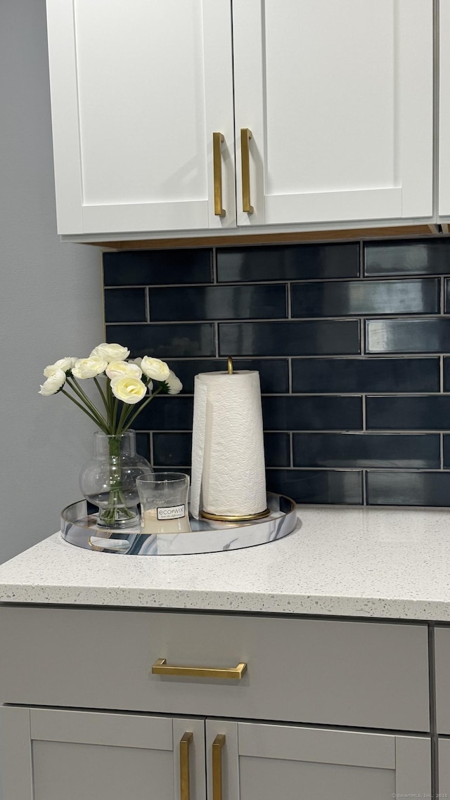 64 Locust St, Bridgeport, CT 06610 - detailed view of backsplash, light stone countertops, white cabinetry, and gray cabinets