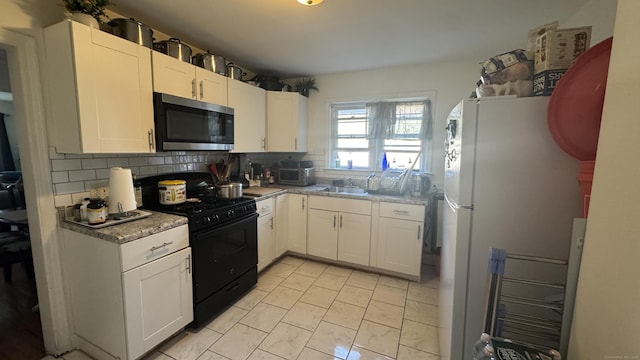 64 Locust St, Bridgeport, CT 06610 - kitchen featuring stainless steel microwave, black range with gas stovetop, freestanding refrigerator, a sink, and tasteful backsplash