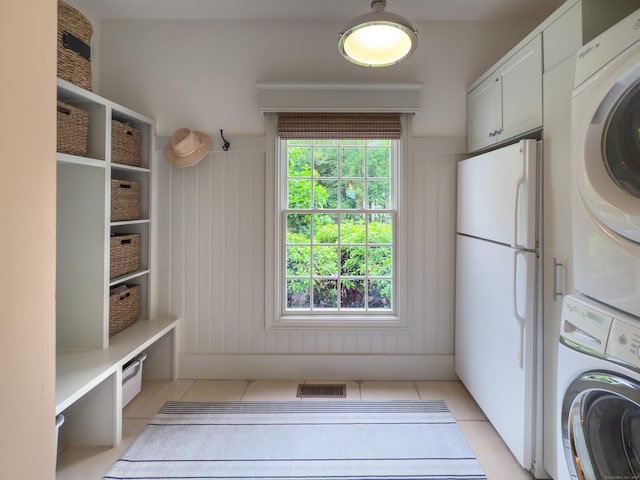 38 Old Trolley Rd, Ridgefield, CT 06877 - washroom with estacked washer and dryer, light tile patterned floors, and cabinet space