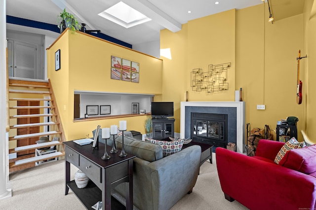 25 Orchard St Unit 14, Stonington, CT 06378 - carpeted living room featuring a high ceiling, a skylight, a glass covered fireplace, beam ceiling, and stairs