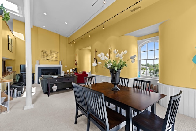 25 Orchard St Unit 14, Stonington, CT 06378 - dining space featuring light colored carpet, wainscoting, a fireplace, a towering ceiling, and a decorative wall