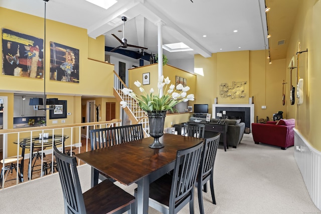 25 Orchard St Unit 14, Stonington, CT 06378 - carpeted dining room featuring a high ceiling, beamed ceiling, stairway, a fireplace, and a skylight