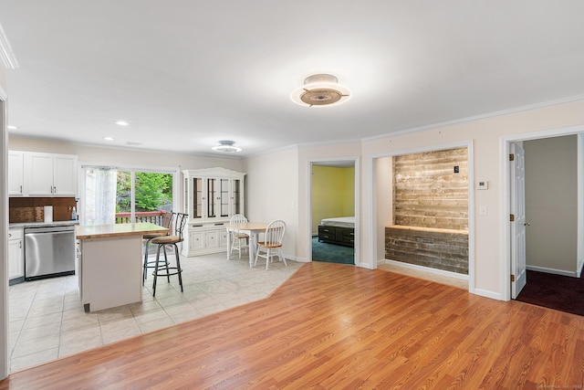 142 Summit St Unit 142, Norwich, CT 06360 - kitchen featuring stainless steel dishwasher, crown molding, a breakfast bar area, light wood finished floors, and white cabinetry