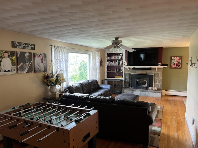 39 Eastwood Rd, Bristol, CT 06010 - living room with a baseboard radiator, a stone fireplace, ceiling fan, and wood finished floors