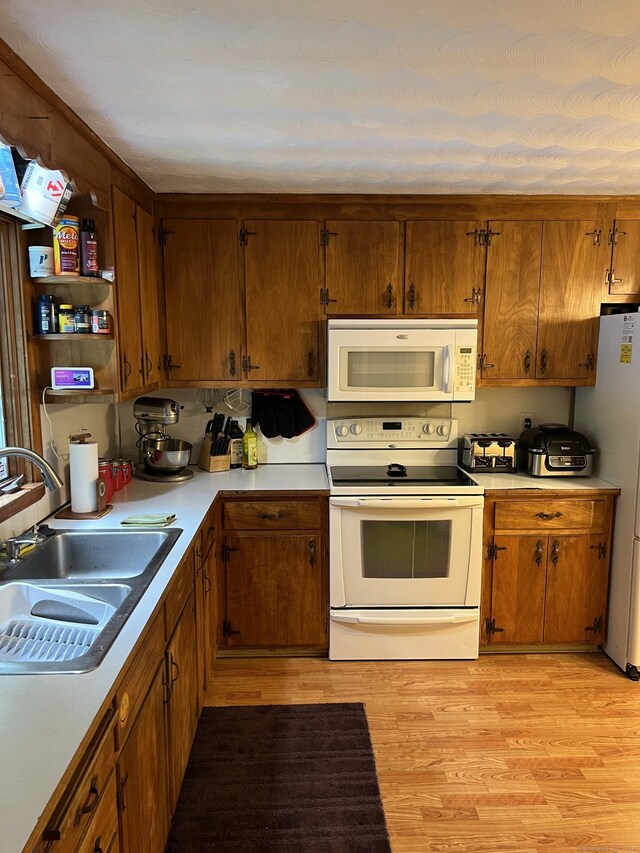 39 Eastwood Rd, Bristol, CT 06010 - kitchen with white appliances, a sink, light countertops, light wood finished floors, and brown cabinets