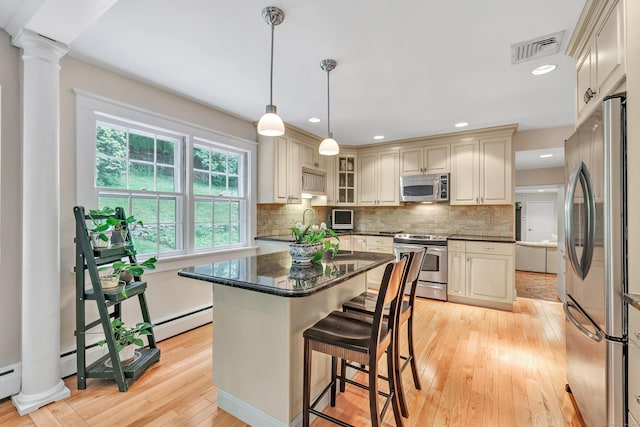 6 Rivergate Woods, Wilton, CT 06897 - kitchen with appliances with stainless steel finishes, baseboard heating, light wood-style floors, a center island, and backsplash