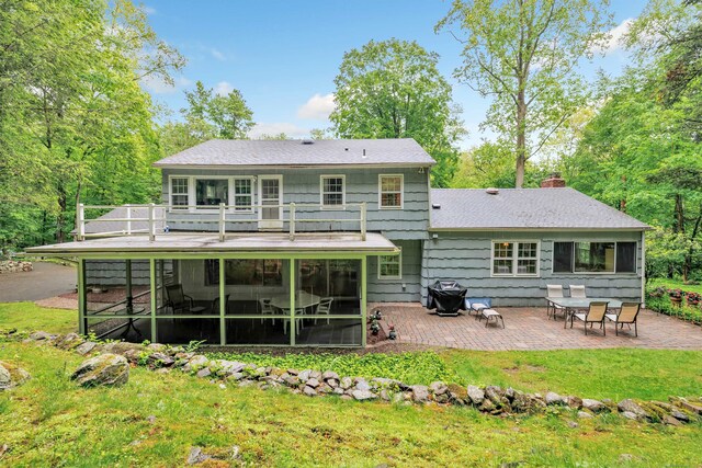 6 Rivergate Woods, Wilton, CT 06897 - rear view of house featuring a sunroom, a patio, a chimney, a lawn, and a shingled roof