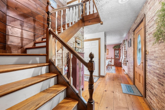 103 Pine St, Columbia, CT 06237 - stairway with brick wall, hardwood / wood-style floors, and a textured ceiling