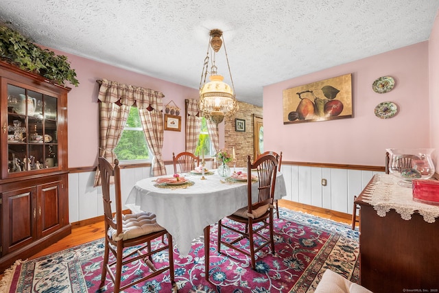 103 Pine St, Columbia, CT 06237 - dining space featuring wood finished floors, a chandelier, a textured ceiling, and a wainscoted wall